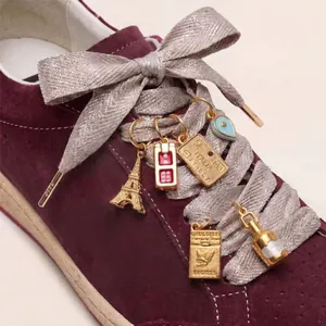 Gros plan de breloques de chaussures dorées avec tour Eiffel et motifs de voyage