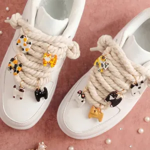 Vue détaillée de diverses breloques de chat mignonnes fixées sur des lacets en corde.