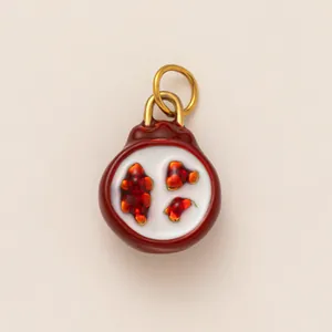 Macro view of a red ceramic pomegranate pendant with gold rings for DIY jewelry making