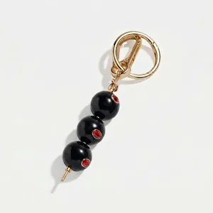 Gedetailleerde macro-opname van elegante olijf-tasbedel met zwarte kralen en goudfinish