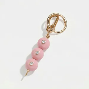 Detailweergave van de roze kralen tassenhanger met sprankelende strass en gouden sluiting