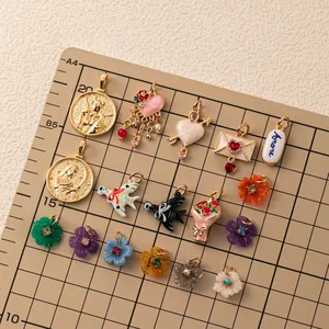 Συλλογή από πολύχρωμα επιχρυσωμένα DIY charms σε πίνακα μέτρησης πλέγματος