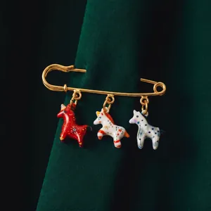 Détail d'une broche épingle dorée avec trois breloques chevaux colorés peints à la main