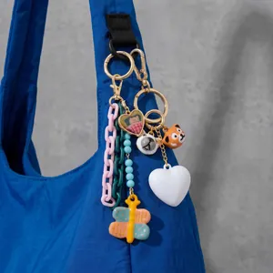 Detailed view of colorful butterfly and heart charms hanging on a blue nylon bag strap