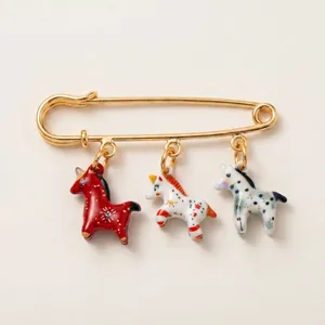 Vue détaillée d'une broche épingle dorée avec trois breloques licornes en émail coloré