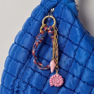 Detailed close-up of a vintage pink shell and woven rope bag charm on blue quilted bag