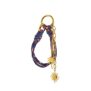 Close-up of stylish woven rope keychain featuring gold sun and palm tree charms.