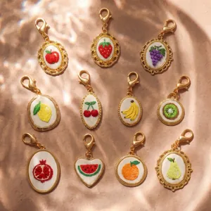 Macro view of various fruit embroidered charms with elegant golden frames and clasps.