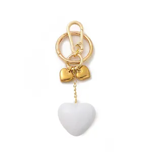 Elegant vintage gold metal and white resin heart-shaped bag charm and keychain detail