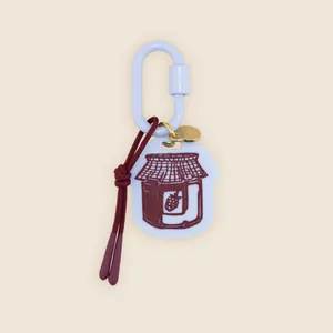 Detail of a hand-drawn jam jar charm on a light blue carabiner keychain with a red cord.