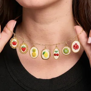 Detailed close-up of colorful handmade fruit embroidery charms on a golden chain necklace
