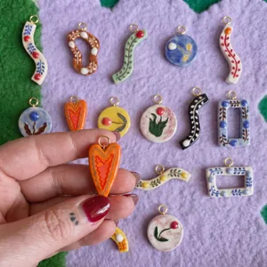 Close-up of hand holding a colorful heart-shaped ceramic pendant with floral patterns
