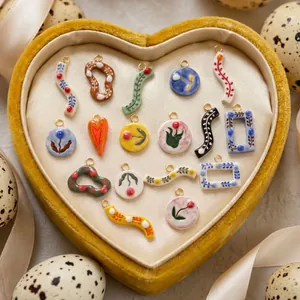 Macro shot of assorted floral ceramic pendants arranged in a yellow heart-shaped velvet box