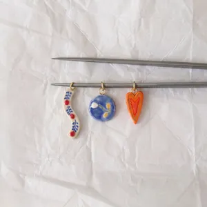 Detailed view of three Nordic pastoral style ceramic charms with flower and heart patterns