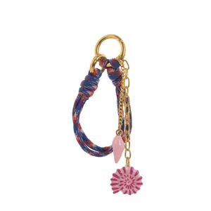Close-up of elegant vintage bag charm featuring blue braided rope and pink shell charms