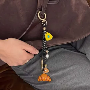 Charming DIY croissant bag charm with 18K gold-plated accessories on brown suede handbag