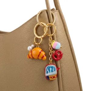 Detailed view of fashion bag charm featuring croissant, pretzel and colorful pendants