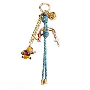 Detailed view of fashion keychain with athlete and ballerina charms in gold finish