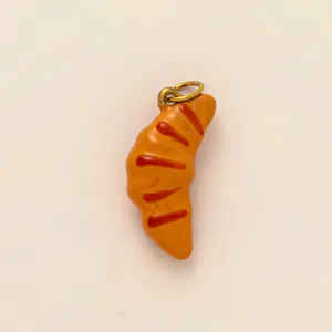 Dettaglio ravvicinato di un ciondolo a forma di croissant realistico per gioielli fai-da-te