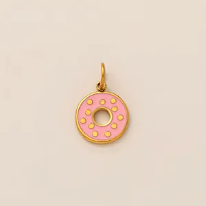 Gros plan d'un pendentif donut en émail rose doré avec des pois dorés