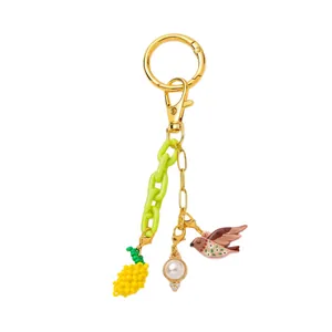 Elegante ciondolo per borsa placcato oro 18K con catena verde perla e pendente uccello floreale