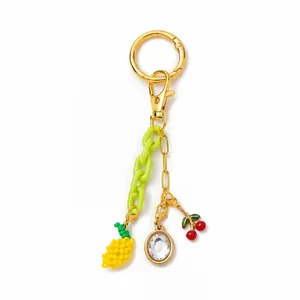 Dettaglio di un elegante ciondolo per borsa dorato con pendenti a forma di frutta