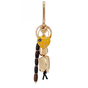 Detailed view of a fashionable bag charm with yellow heart and dark wooden beads