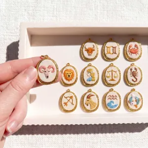 Detailweergave van 12 geborduurde dierenriem hangers in gouden montuur.