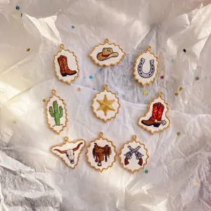 Close-up of cowboy style embroidered pendants with boots, hats, and cactus designs.