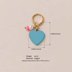 Detailed macro view of blue heart charm with pearl and copper gold-plated earring hoop