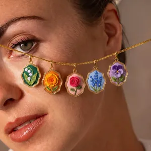 Nahaufnahme von fünf bunt bestickten Blumenanhängern an einer schicken goldenen Kette