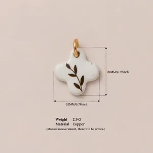 Detail shot of a white flower pendant with leaf print and gold-colored copper bail