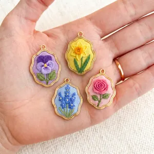 Detailaufnahme von vier handgefertigten Stickanhängern mit bunten floralen Motiven