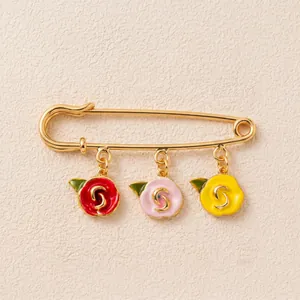 Vue détaillée d'une broche épingle dorée ornée de trois fleurs en émail colorées