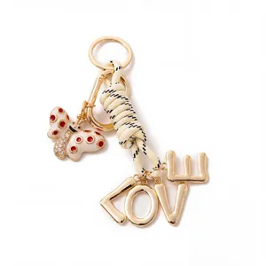 Close-up of stylish DIY bag charm with gold butterfly and braided cord LOVE letters