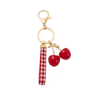 Stylish cherry bag charm featuring red checkered strap and polished gold hardware for women