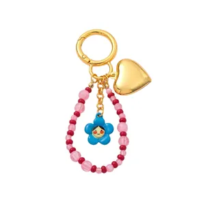 Elegant gold heart bag charm with pink beaded loop and cute blue flower doll pendant