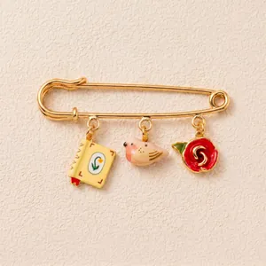 Vue détaillée de la broche épingle à nourrice dorée avec breloques oiseau et rose.