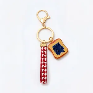 Close-up of stylish toast and jam charm keychain with red houndstooth strap
