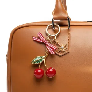 Close-up detail of cherry bag charm with red gingham bow and gold star pendant