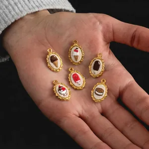 Close-up of assorted embroidered dessert pendants held in hand with gold steel frames