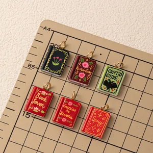 Close-up of colorful magic book pendants with creative themes on a grid mat.
