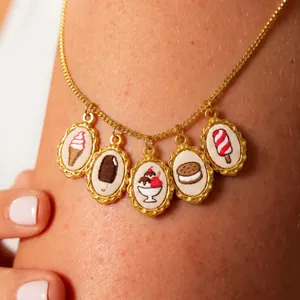 Detailed close-up of embroidery charms featuring sweet dessert motifs on gold chain