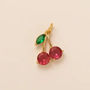 Close-up of a sparkling cherry pendant with red and green faceted stones in gold-tone setting