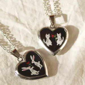 Detailansicht von herzförmigen Medaillons mit süßen Emaille-Katzen- und Hasen-Designs