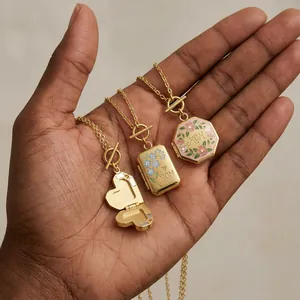 Detailopname van drie vintage gouden medaillon kettingen met bloemen en MOM tekst