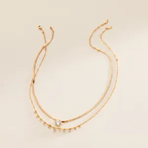 Detailed macro view of a gold double-layer necklace with snake chain and zircon accents.