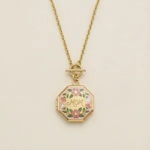 Detail van een achthoekige gouden medaillon ketting met roze emaille bloemen en MOM gravure