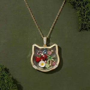 Gros plan d'un collier médaillon chat en or avec des breloques nature colorées