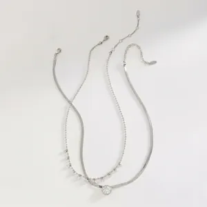 Detailed macro shot showing the elegant silver snake chain and layered zircon charm necklace